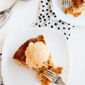 A image of apple pie with a scoop of vanilla ice cream on it.